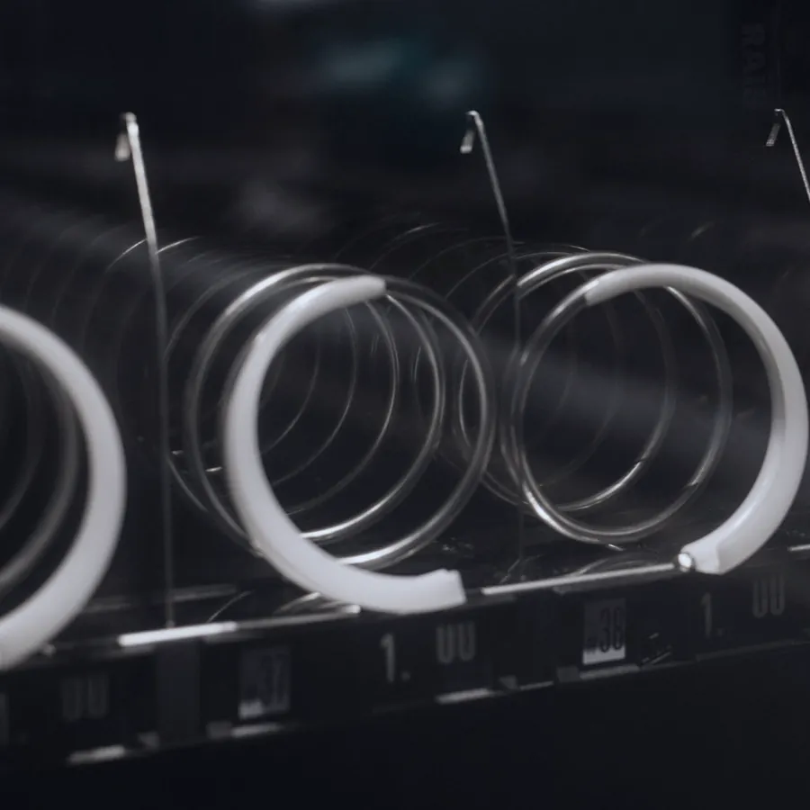 Close-up of empty metal spiral coils inside an old snack machine.